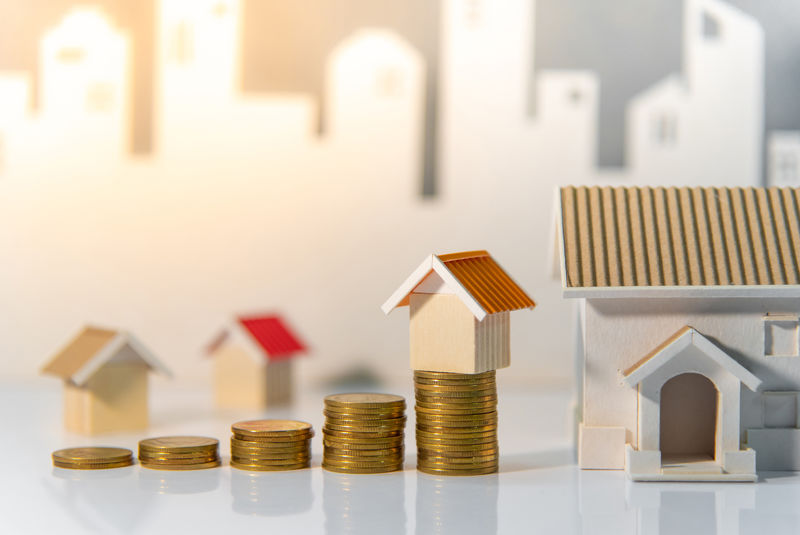 房地产投资或住房抵押贷款利率-梯形图概念-桌子上的硬币堆和房子模型都是白色的城市背景-资金投资和业务增长