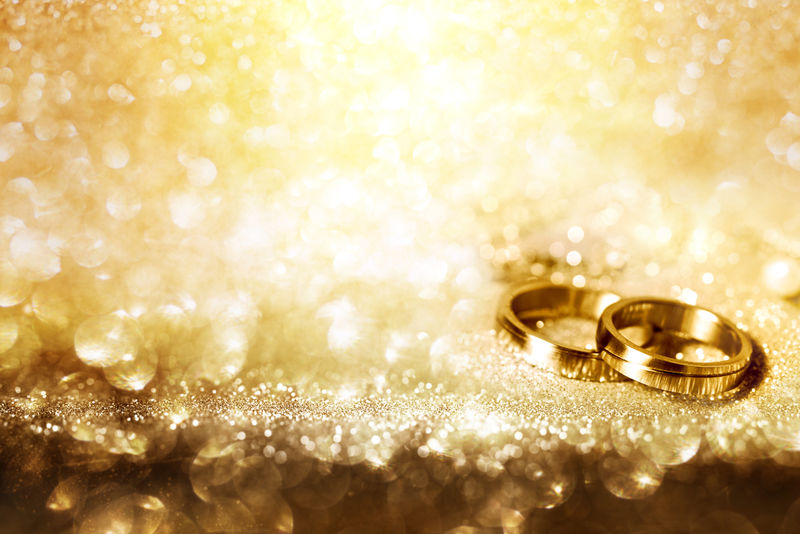 喜庆金色背景上的结婚戒指-带闪亮的博克效果