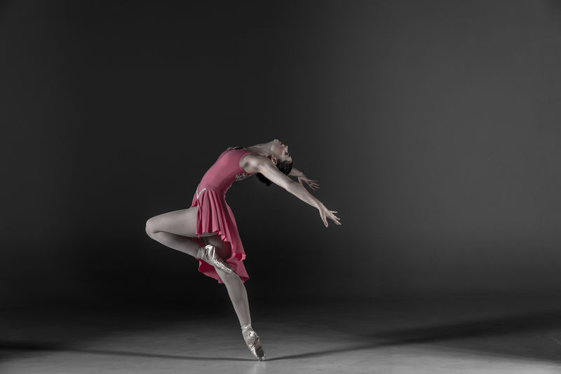 指尖上的芭蕾舞演员在黑暗中向后倾斜