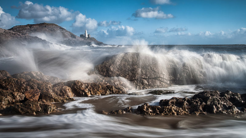 在南威尔士的高尔半岛上汹涌的海浪和咕哝的灯塔
