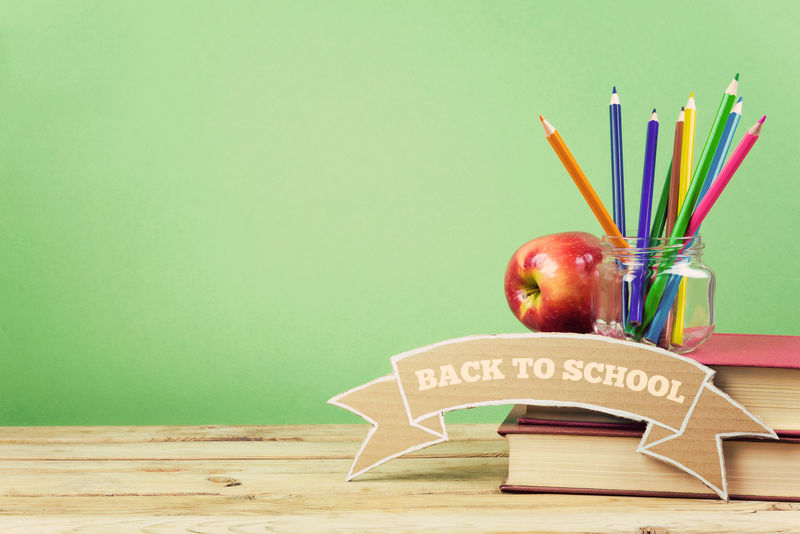 回到学校背景书铅笔和苹果放在木桌上