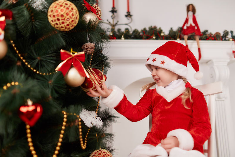 穿着新年礼服的快乐小女孩-在圣诞树的背景下摆姿势