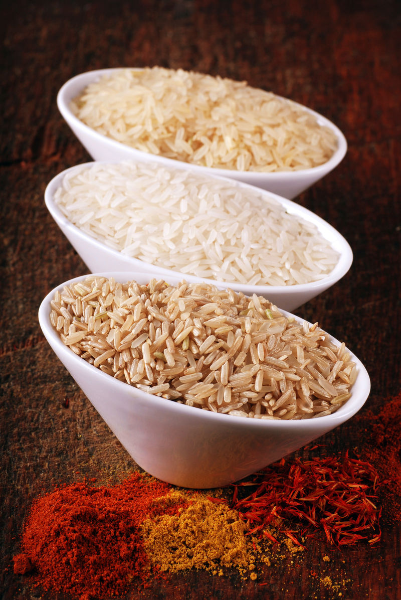 三碗不同类型的大米：野生大米-白色（茉莉）大米-糙米和印度香料在木板上-选择性聚焦