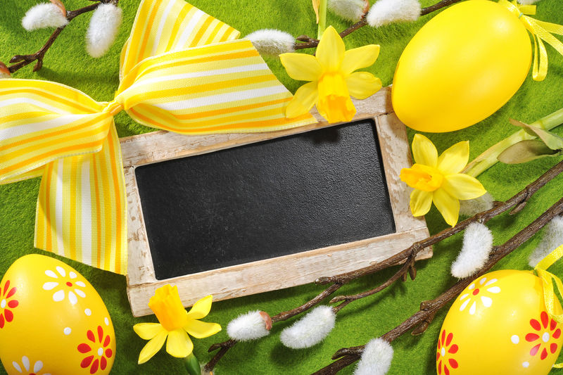 带复印空间的复活节黑板黄色复活节彩蛋水仙和桌布上的阴柳