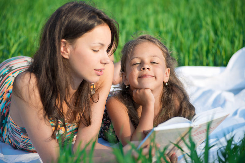 在春夏公园野餐时-快乐的女孩们在草地上读书