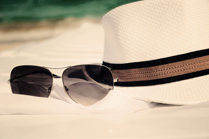 在大海和沙滩的背景上的彩色图像白色帽子和太阳镜-水平的