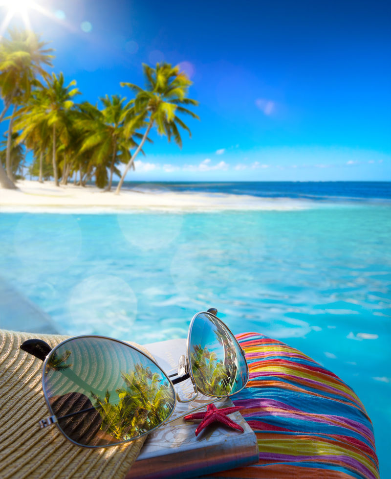 热带海滩上的草帽包和太阳镜