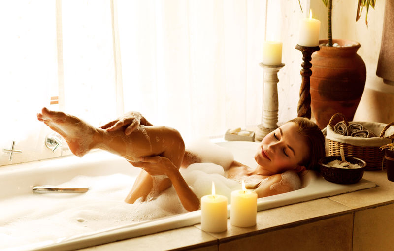 一个女人在豪华温泉沙龙放松的照片-年轻美丽的女士在家洗澡的照片-漂亮的女性沐浴肥皂泡沫和蜡烛在酒店房间-可爱的女孩在按摩浴缸放松