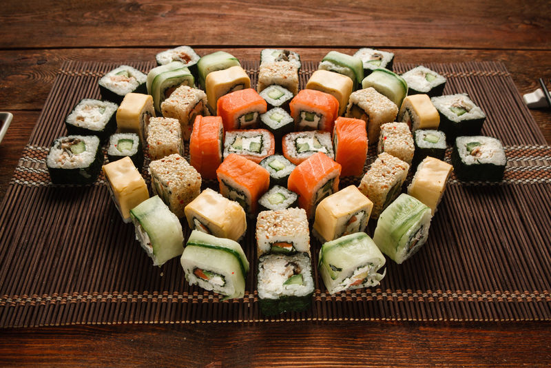 美味的五颜六色的新鲜日本寿司卷，放在棕色草席上，特写镜头。美食艺术，传统海鲜，豪华餐厅菜单照片。