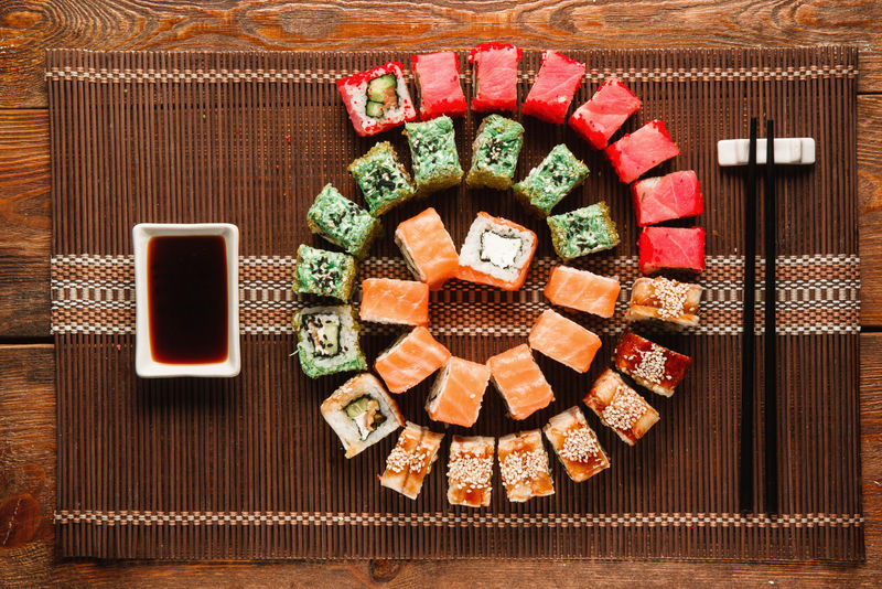 日本寿司，美食艺术。一大套新鲜的面包卷在棕色的草席上呈彩色螺旋状，平放。豪华餐厅菜单照片，传统东方美食。