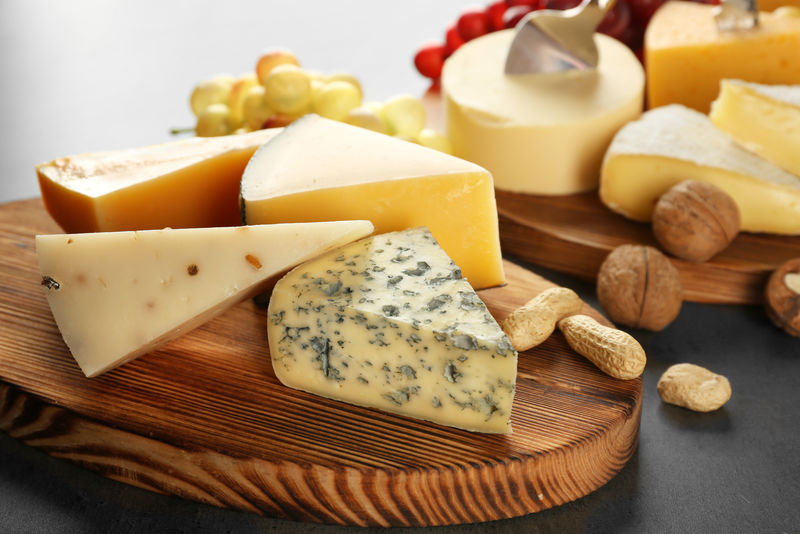 灰色背景中各种奶酪和坚果的木板