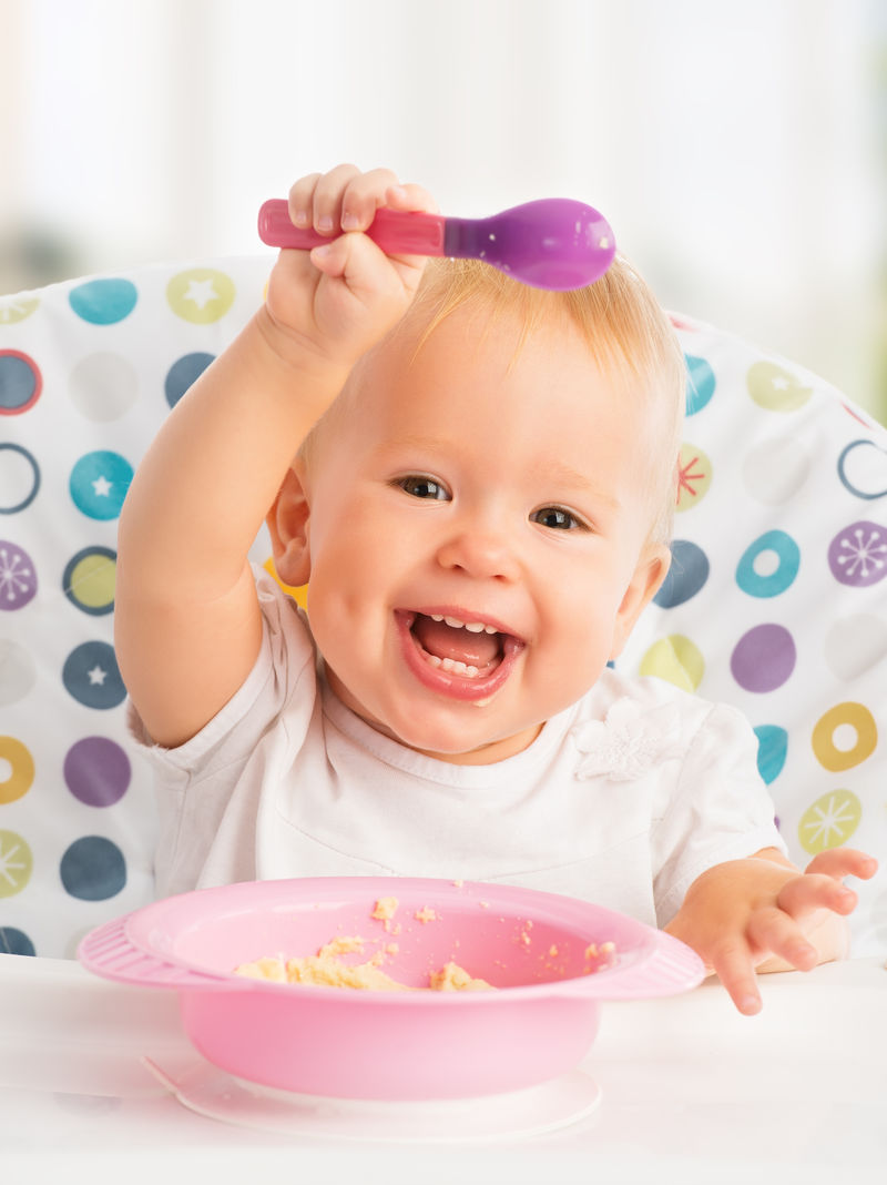 快乐快乐的婴儿用勺子吃自己