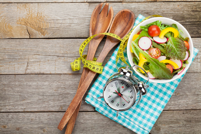 新鲜健康沙拉和木桌上的测量带-健康食品