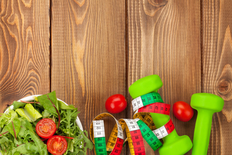 哑铃、卷尺和健康食品放在木制桌子上-有复印空间-健康与健康