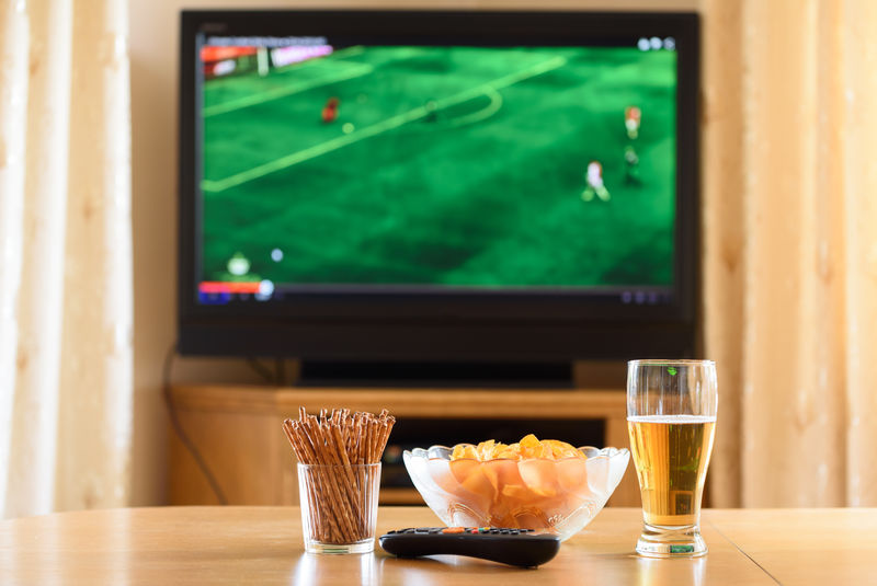 电视、电视（足球、足球比赛）和桌上小吃-库存照片