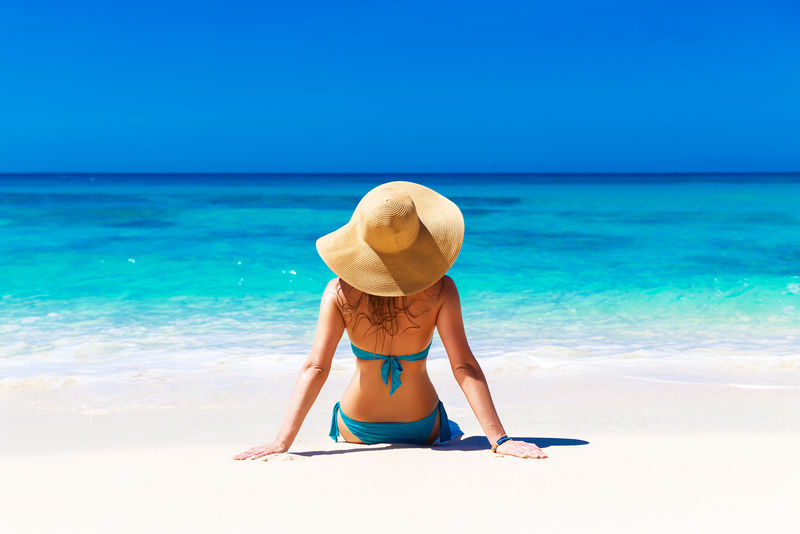 热带海滩上戴草帽的年轻女孩-暑假概念