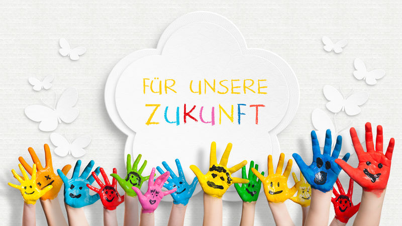 五彩斑斓的手画在装饰墙前-用德语写着“为我们的未来”