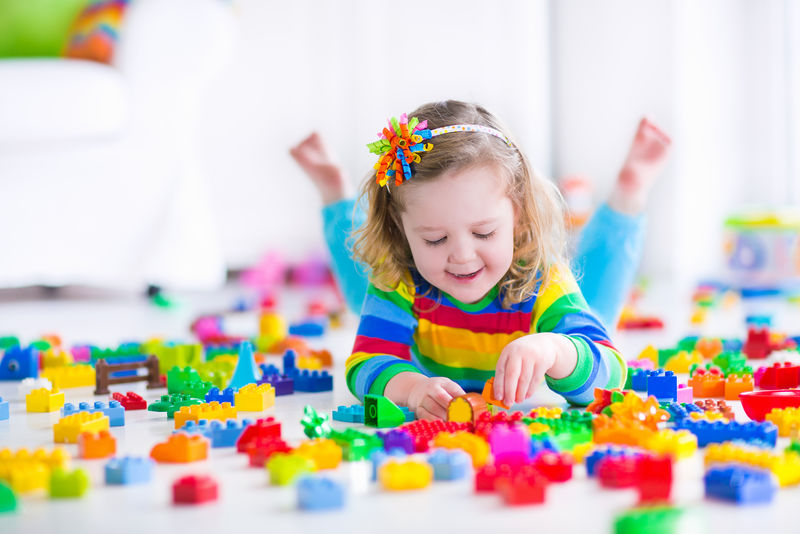 可爱有趣的学龄前小女孩在一个丰富多彩的衬衫玩建筑积木在阳光幼儿园室的塔楼-孩子们玩-日托儿童-儿童玩具