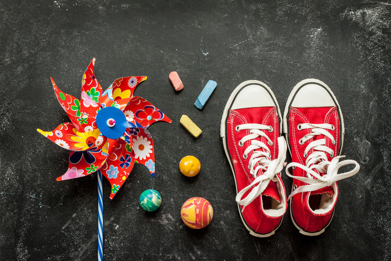 黑色黑板上的玩具和红色运动鞋-童年-假期或暑期乐趣的概念-具有自由文本空间的背景布局