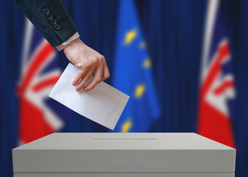 英国的选举或公投。投票者手里拿着信封。背景是英国和欧盟的旗帜。