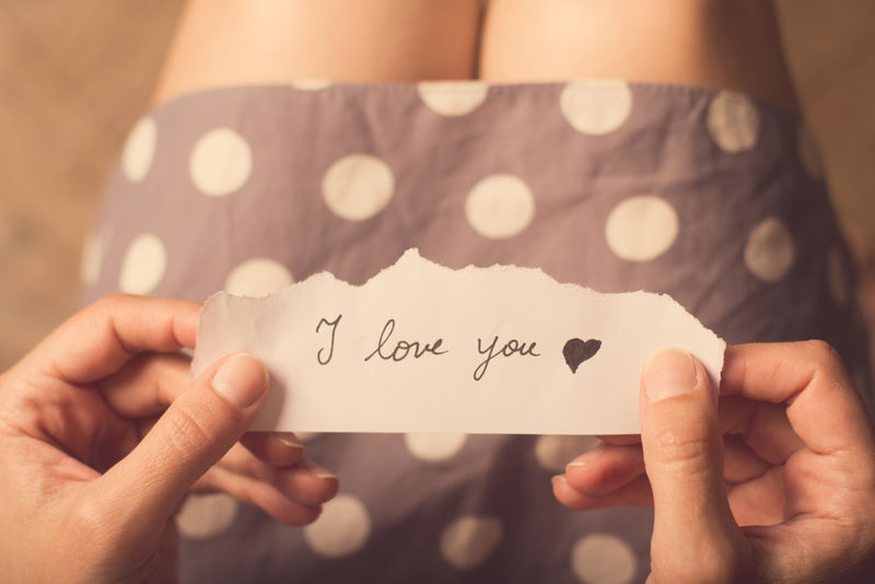 女人拿着一张纸条，上面写着“我爱你”