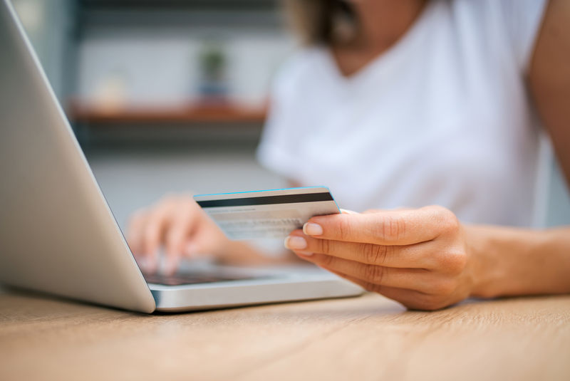 女性使用信用卡进行网上购物的特写图片
