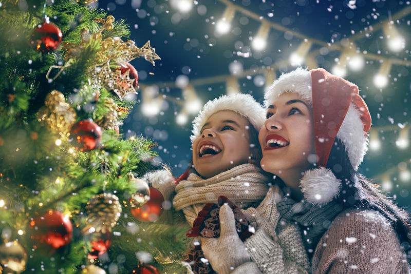 圣诞快乐-节日快乐！妈妈和女儿在户外装饰圣诞树-圣诞之夜-爱好肖像的家庭