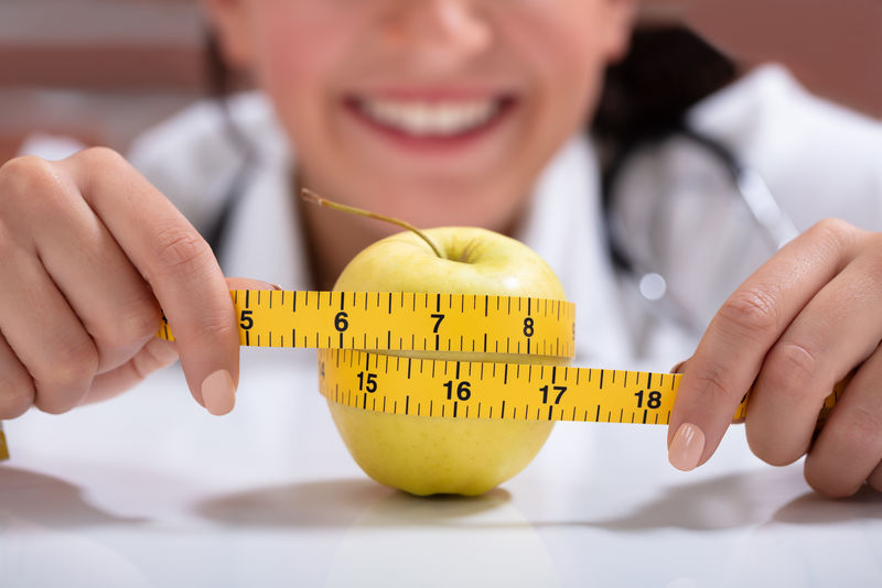 女营养师用卷尺测量整只苹果的特写镜头