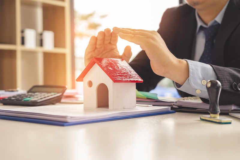 房地产经纪人或银行家用手盖木屋-住房保障和家庭保险概念