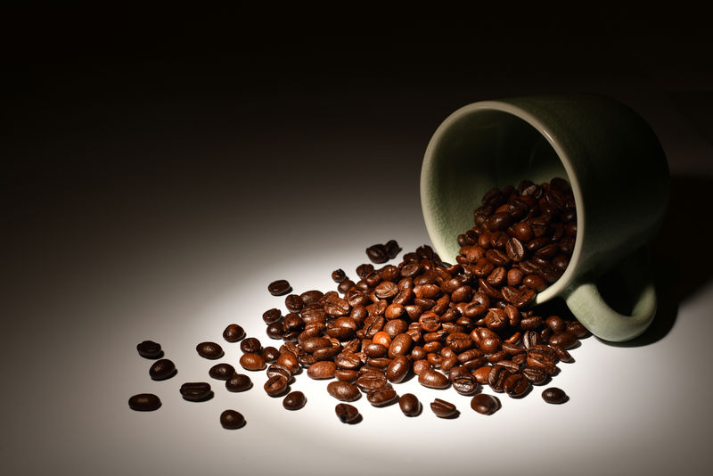 咖啡杯中的咖啡豆在黑暗背景下的聚光灯下
