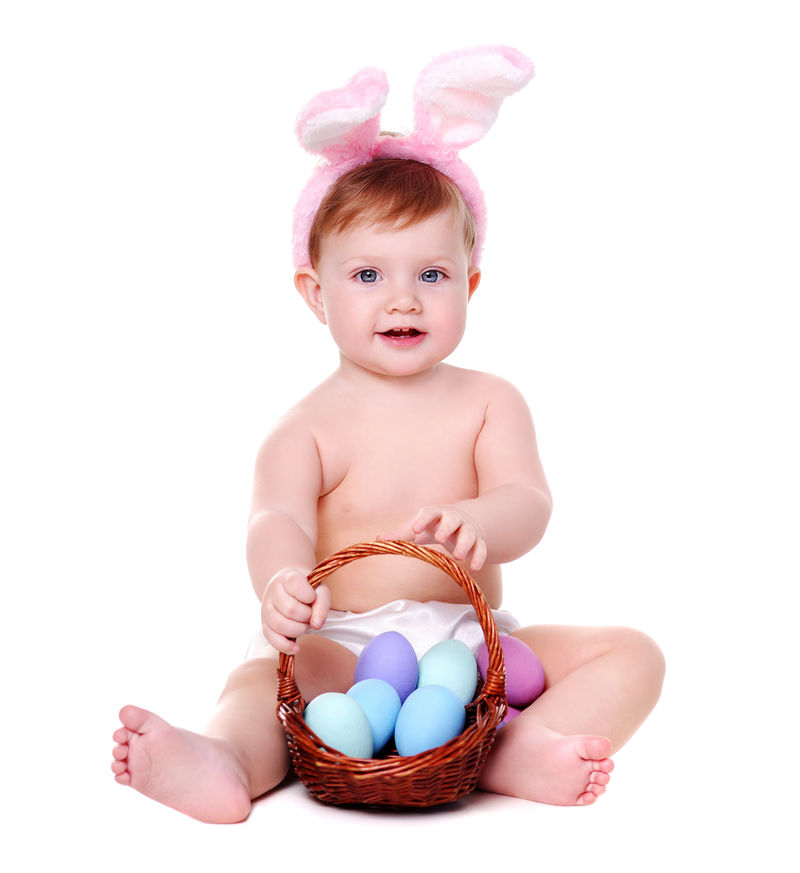 抱着复活节彩蛋篮子的坐着的女婴