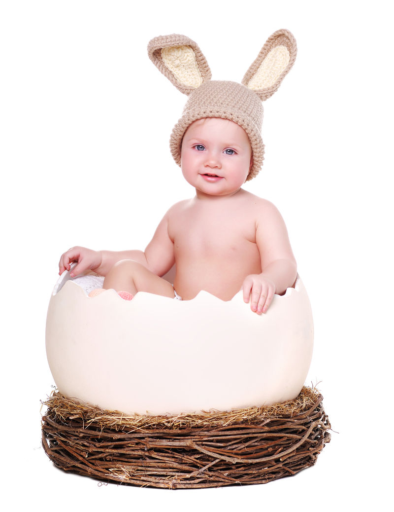 戴着兔子帽坐在大鸡蛋里的女婴