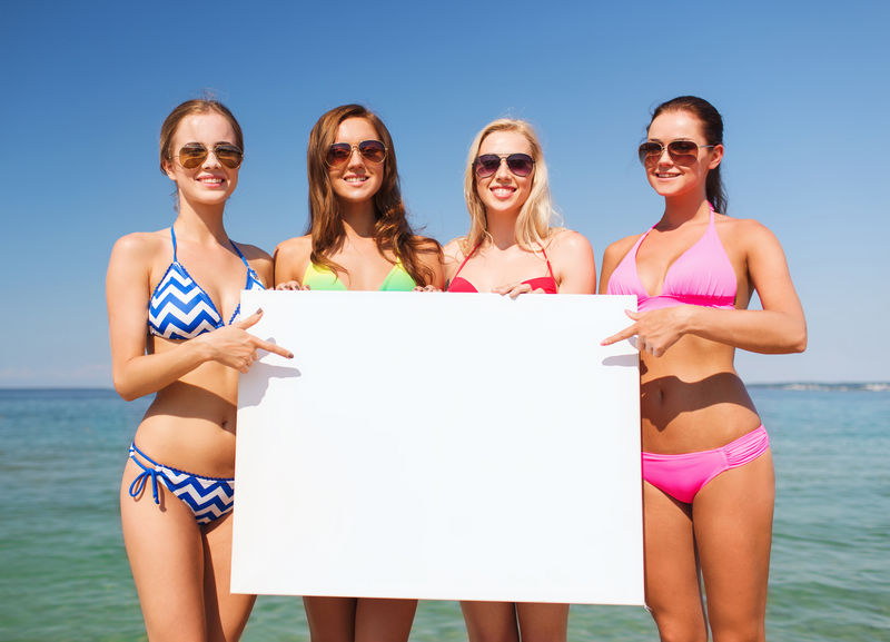 一群在沙滩上戴着白板微笑的女人