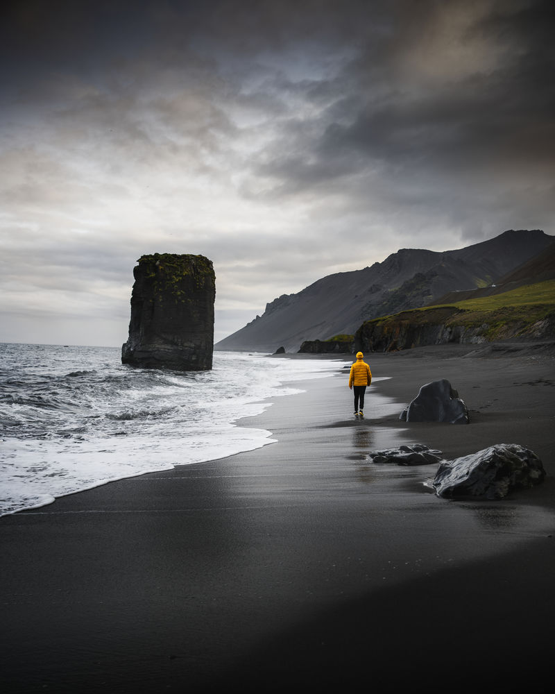 在冰岛的一个黑色海滩上散步的人