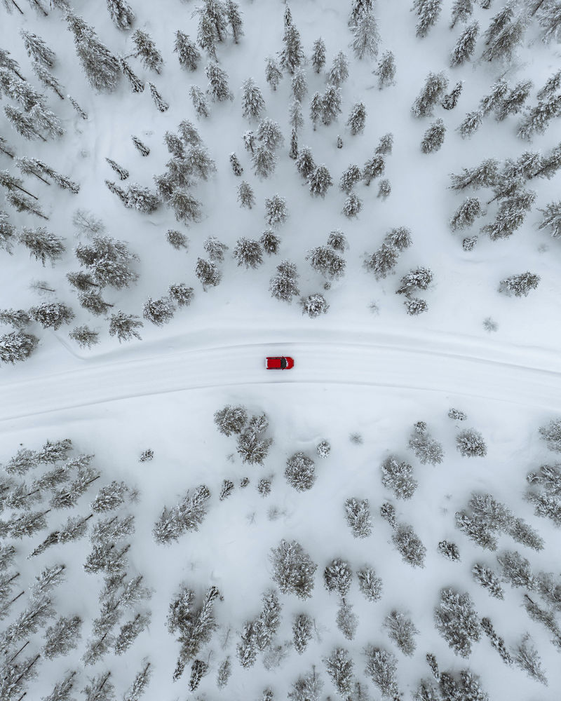 芬兰拉普兰一辆红色汽车在雪域森林中行驶
