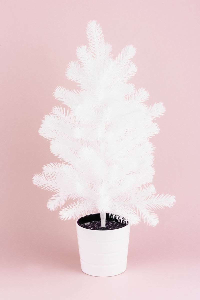 粉红色背景的白色人造圣诞树