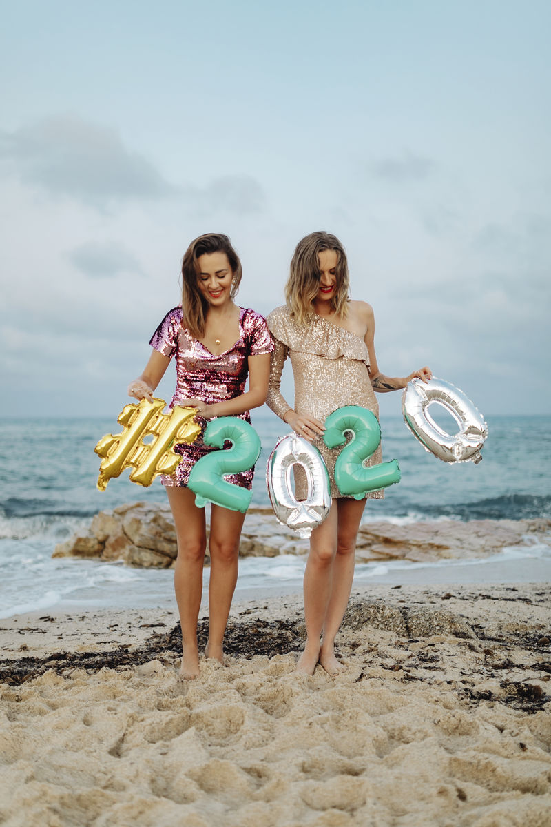 在海滩派对上女孩们拿着一个2020年的铝箔气球