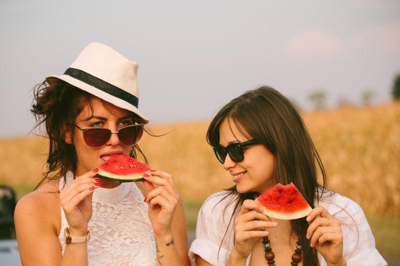 两个年轻的美女在乡间公路旁吃西瓜