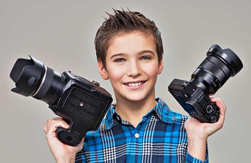 小男孩拿着两个相机