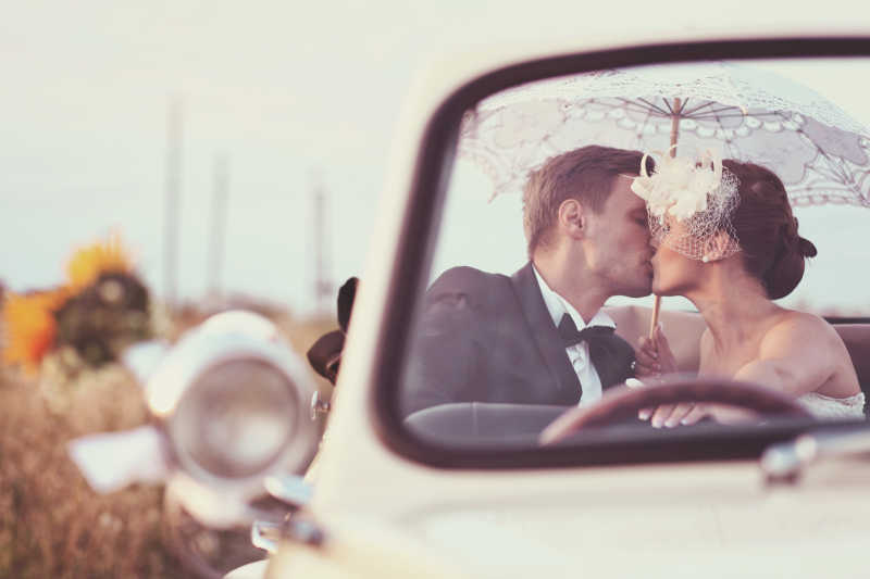 白色老爷车里亲吻的新婚夫妻