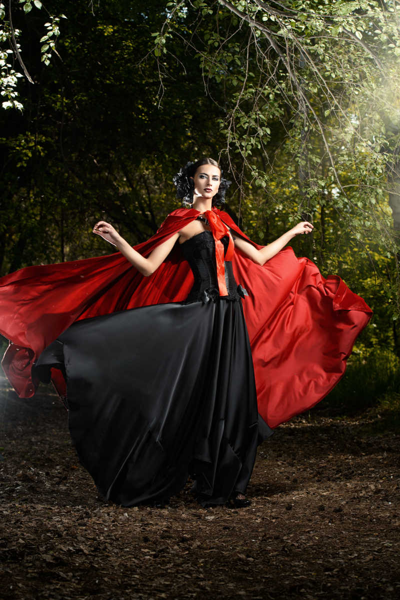 魔法森林中穿红色斗篷和黑色礼服的女人