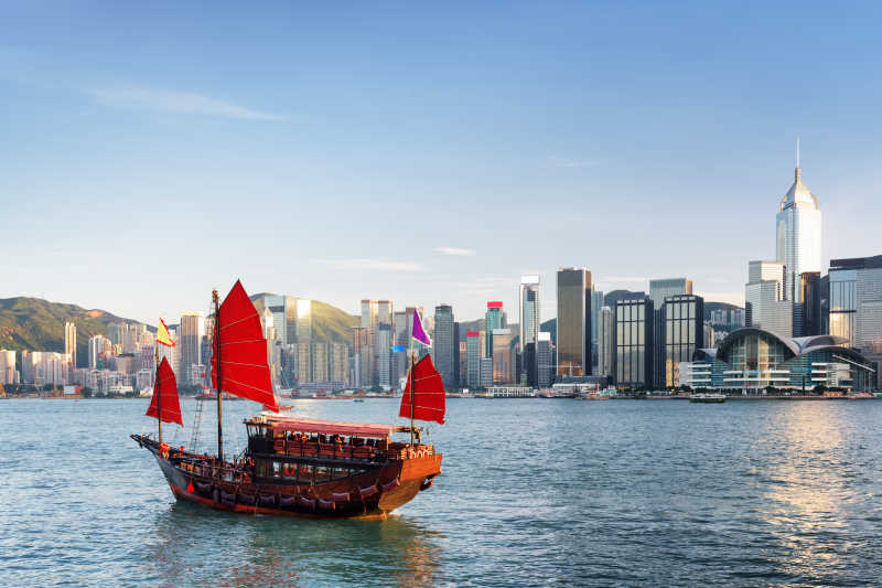 香港大楼背景前的红色拉货帆船
