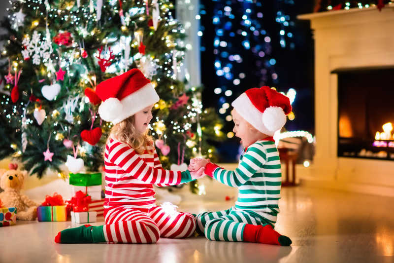 圣诞树下穿睡衣的孩子正在玩耍