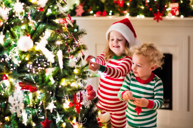 穿睡衣的孩子正在装饰圣诞树