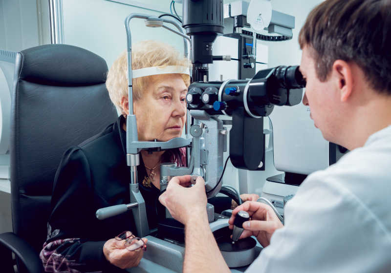 医生通过眼科设备来检查病人的眼睛