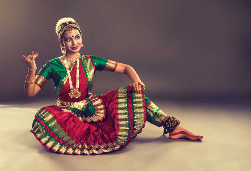 灰色背景下穿着漂亮服装跳舞的印度舞女