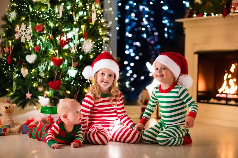 圣诞树下穿睡衣的孩子一起玩耍微笑