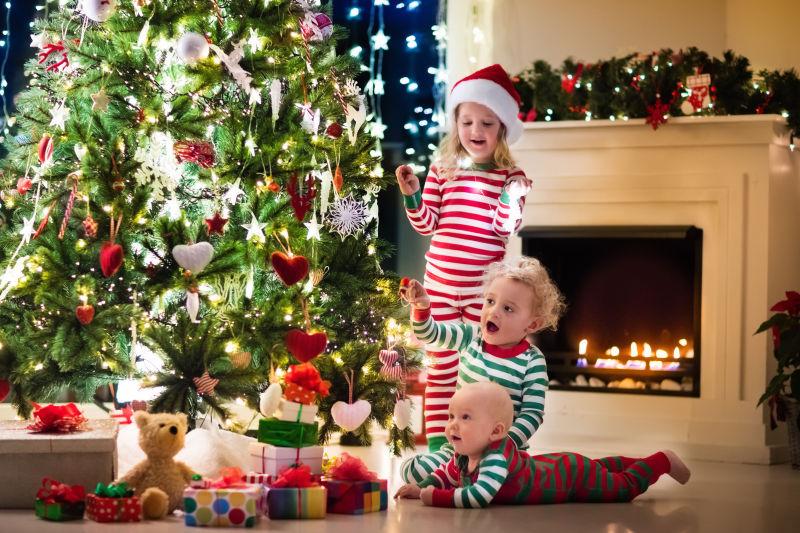 圣诞树下穿睡衣的孩子一起装饰