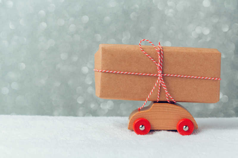玻璃窗前的雪地上的玩具车上的礼品盒