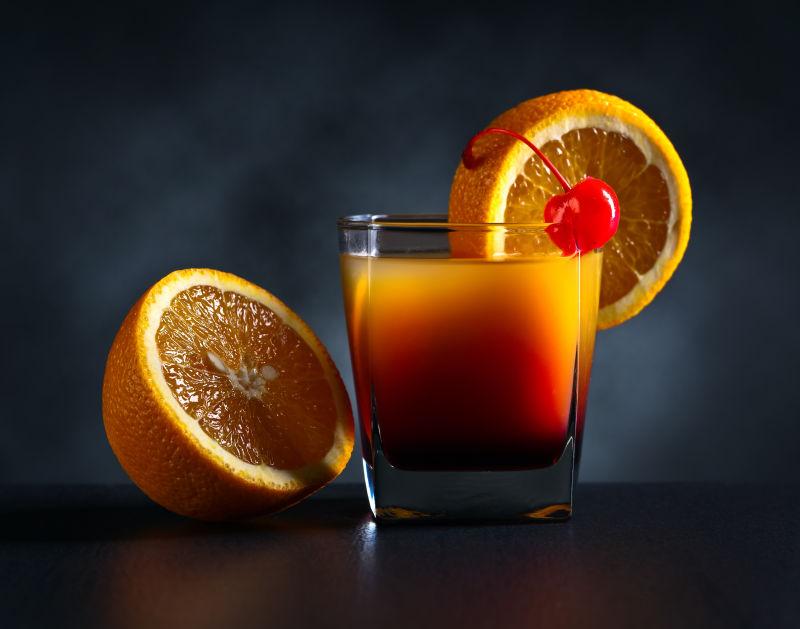 黑色背景上的橙色鸡尾酒和橙子